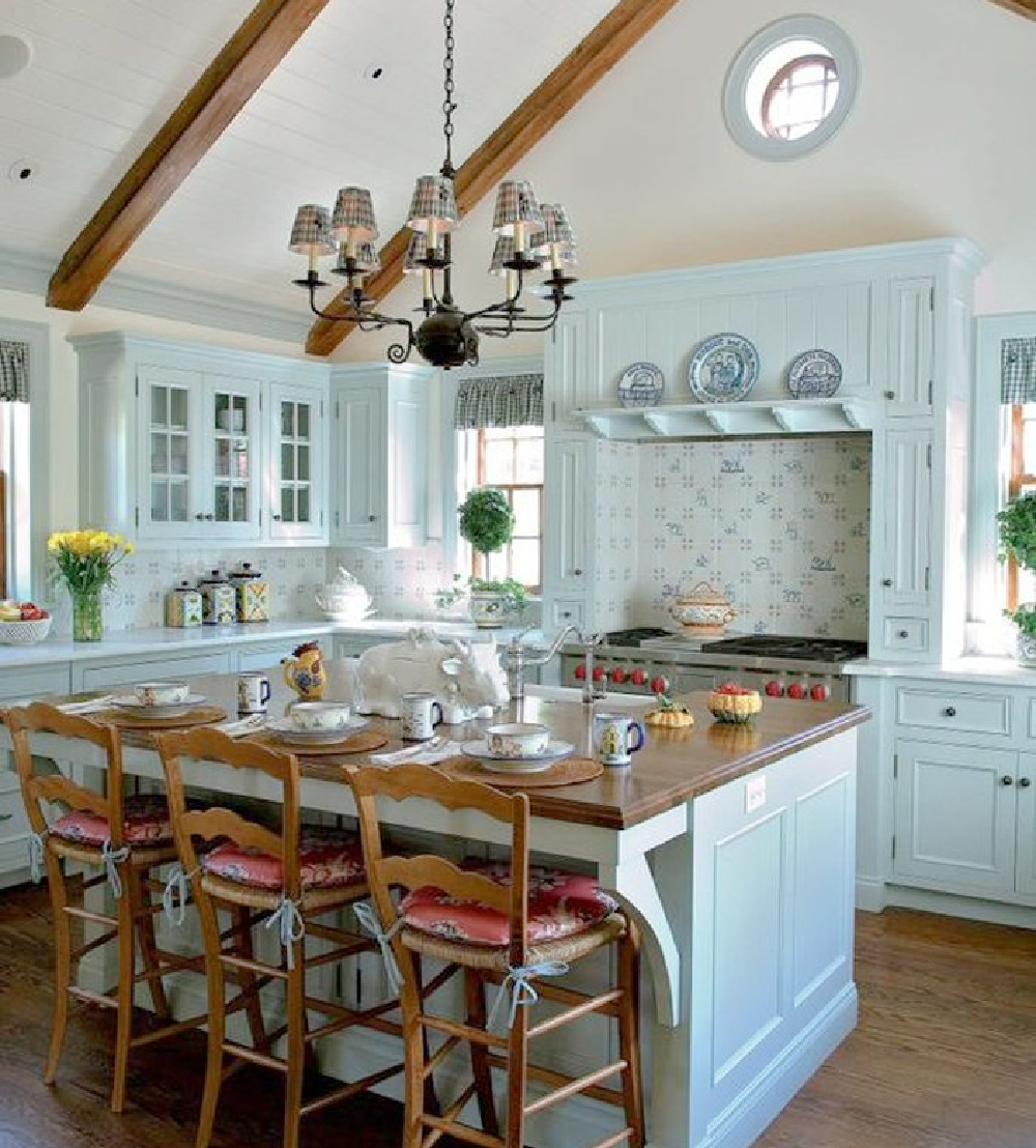 Turquoise kitchen cabinets in a charming country kitchen with round window and rustic beams - HomeBNC. #bluekitchens #colorfulkitchens