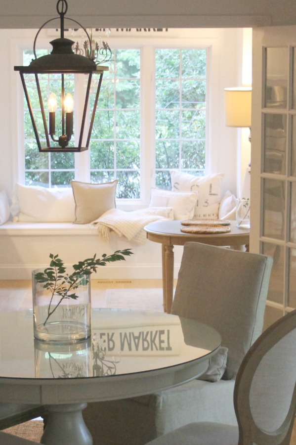 French Nordic style and Belgian influence in a dining room and kitchen with window seat by Hello Lovely Studio. Wall paint color is Benjamin Moore White.