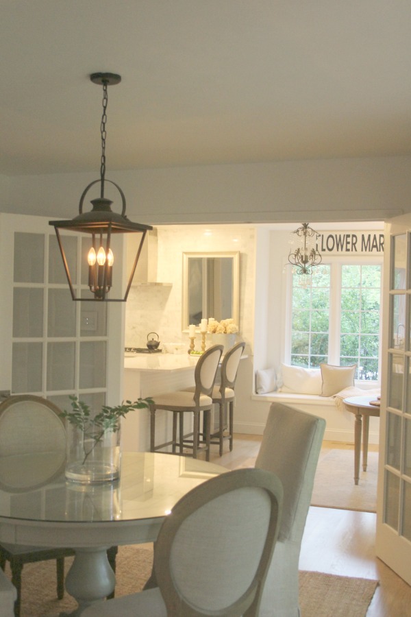 Belgian linen dining chairs and round table in our dining room adjacent to the kitchen. Photo: Hello Lovely Studio. #hellolovelystudio #diningroom #belgianstyle #belgianlinen #lantern #serenedecor #frenchcountry