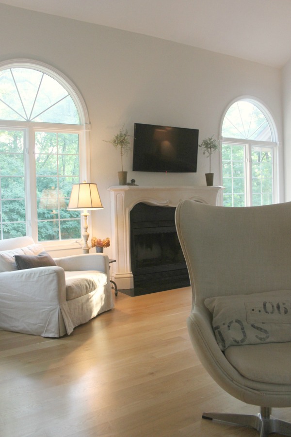 Belgian linen upholstered furniture, white oak flooring, and French stone fireplace in living room. Come see more of my home in Hello Lovely House Tour in July. #hellolovelystudio #timeless #tranquil #interiordesign #europeancountry #europeanfarmhouse #simpledecor #serenedecor