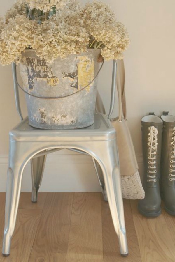 Farmhouse style. Metal French bistro chair with vintage bucket of hydrangea. Hello Lovely Studio. #metalchair #frenchchair #bistrochair #hydrangea #farmhousestyle #hunterboots