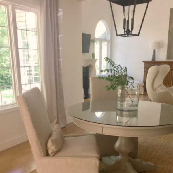 Dining room with Belgian linen slipcovered side chairs and round table. Carriage style lantern pendant over table. Hello Lovely Studio.