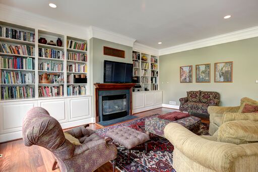 Traditional decor in a family room with sage green walls and built in bookcases.