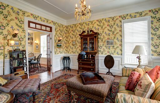 Yellow floral wallpaper in French country living room with chandelier.