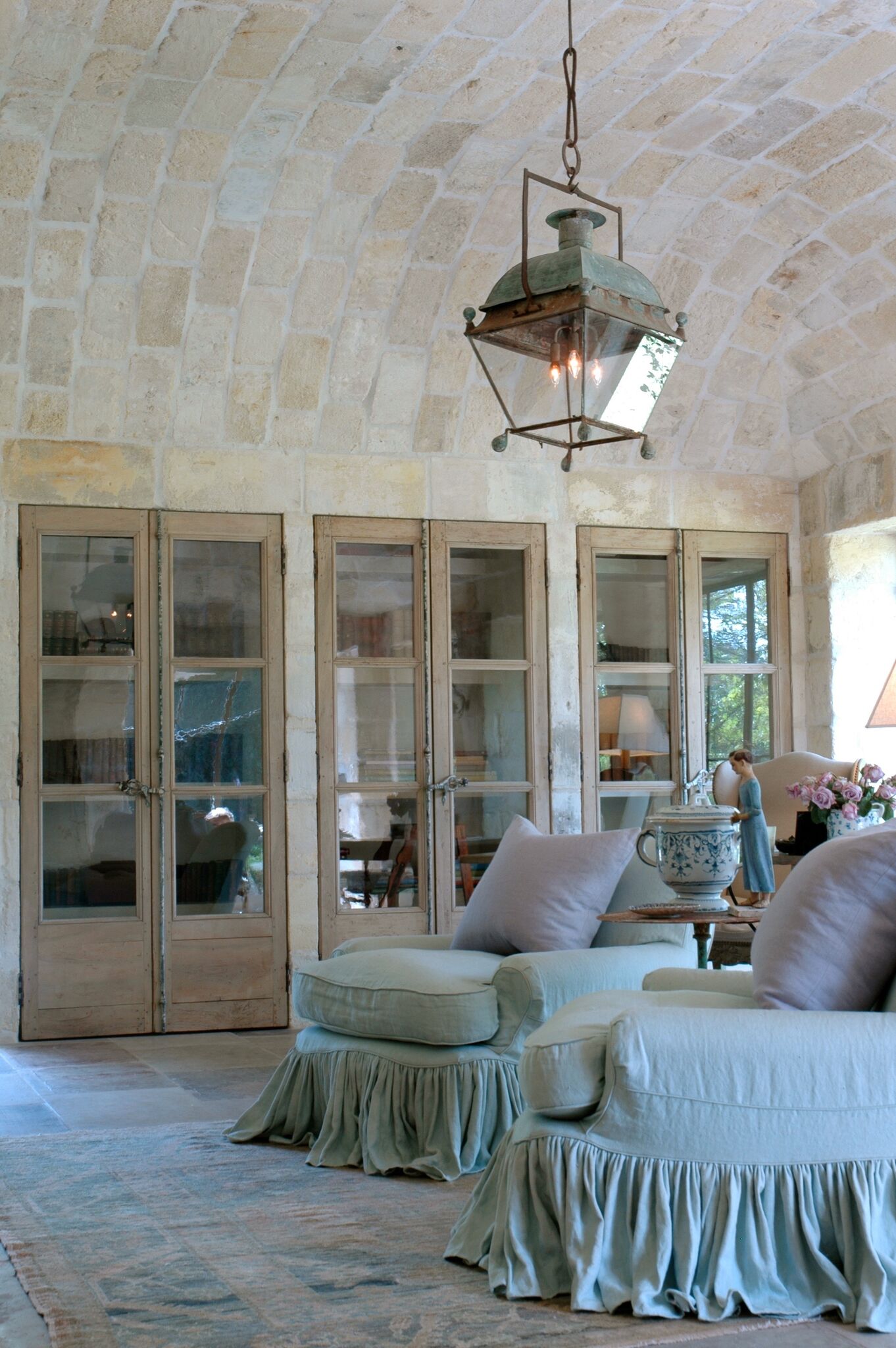 Three pairs of 18th century French doors, barrel vaulted ceiling clad in 17th century stone from a French Vineyard, and blissful upholstered pieces grace Ruth Gay's office.#chateaudomingue #ruthgay #limestone #antiques #lantern #frenchcountry #frenchfarmhouse #europeanfarmhouse #europeancountry