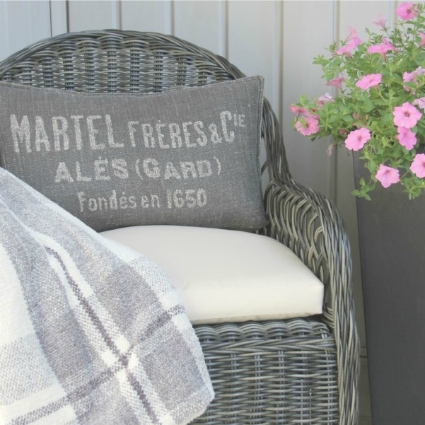 Grey kubu rattan patio chair with ivory cushion, French pillow, and plaid throw. Design by Hello Lovely Studio. #kubu #patiochair #outdoorfurniture #rattan