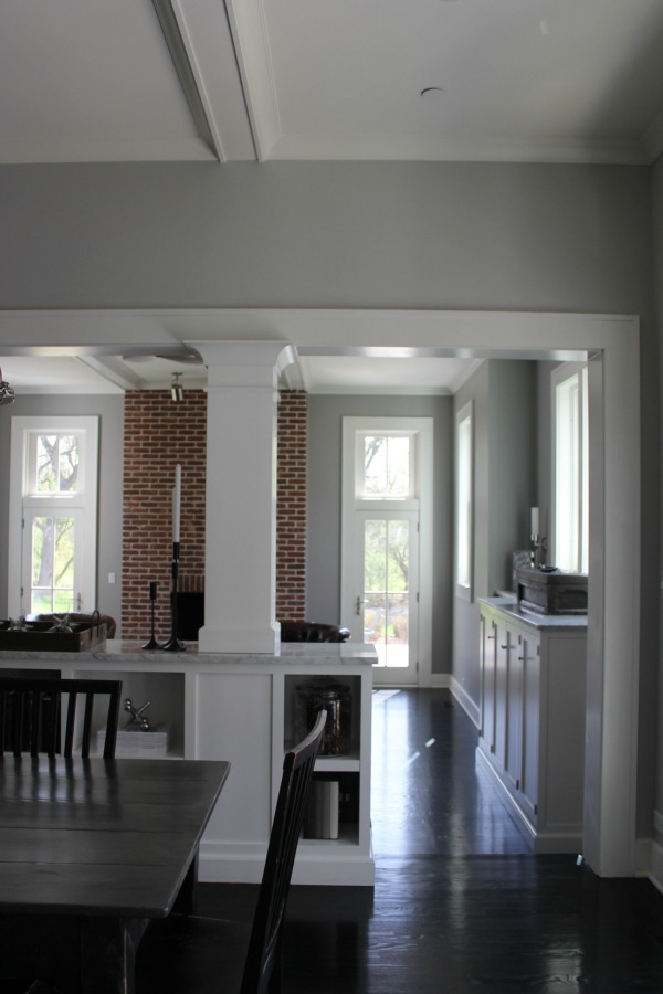 Architectural details are grand in a restored 1875 farmhouse kitchen and family room. Score the exact medium grey paint colors on Hello Lovely. #interiordesign #industrialfarmhouse #benjaminmoorestoningtongray #farmhousearchitecture #blackfloors