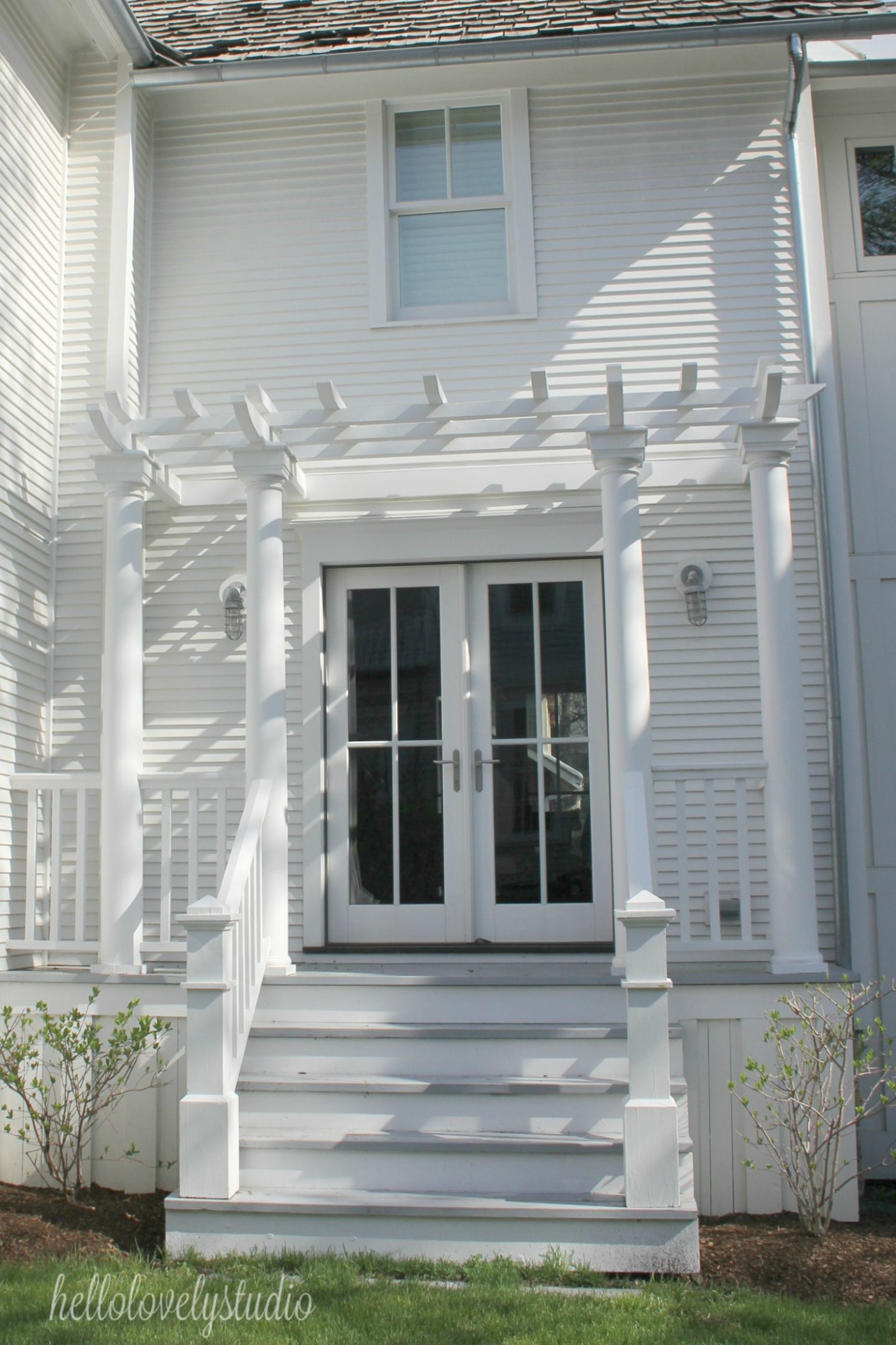 White modern farmhouse exterior with cedar siding, board and batten, metal galvalume roof, and black trim accents. Come see more! Photo by Hello Lovely Studio. #modernfarmhouse #exterior #whitefarmhouse #boardandbatten #housedesign #farmhousearchitecture #hellolovelystudio