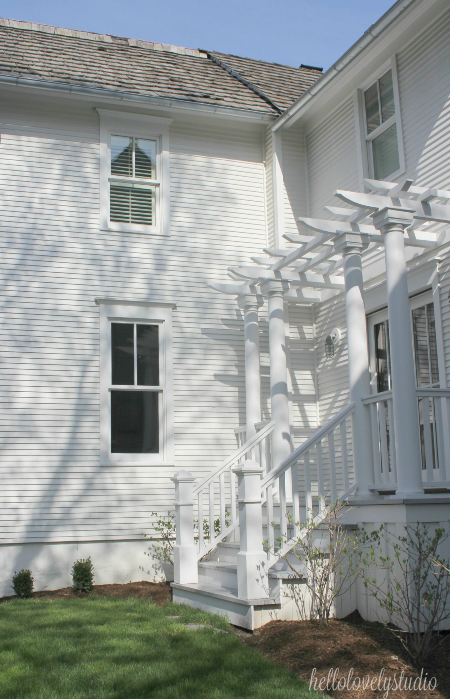 White modern farmhouse exterior with cedar siding, board and batten, metal galvalume roof, and black trim accents. Come see more! Photo by Hello Lovely Studio. #modernfarmhouse #exterior #whitefarmhouse #boardandbatten #housedesign #farmhousearchitecture #hellolovelystudio