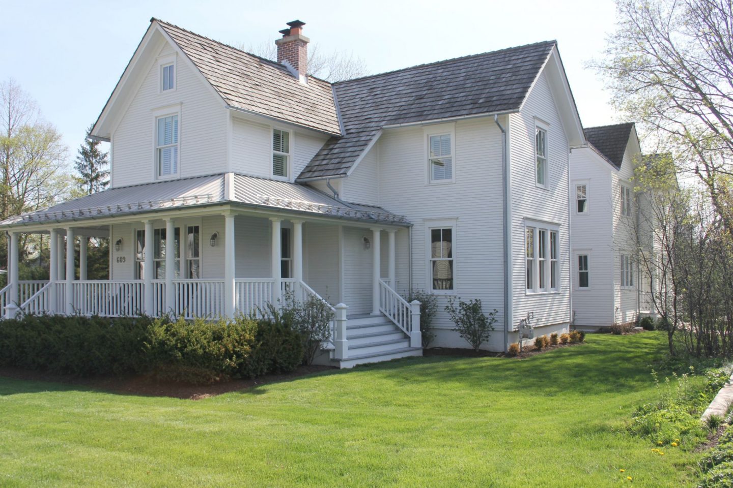 White modern farmhouse exterior with cedar siding, board and batten, metal galvalume roof, and black trim accents. Come see more! Photo by Hello Lovely Studio. #modernfarmhouse #exterior #whitefarmhouse #boardandbatten #housedesign #farmhousearchitecture #hellolovelystudio