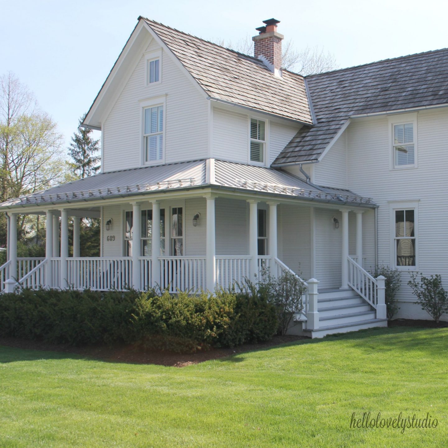 White modern farmhouse exterior with cedar siding, board and batten, metal galvalume roof, and black trim accents. Come see more! Photo by Hello Lovely Studio. #modernfarmhouse #exterior #whitefarmhouse #boardandbatten #housedesign #farmhousearchitecture #hellolovelystudio