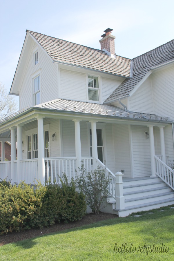 White modern farmhouse exterior with cedar siding, board and batten, metal galvalume roof, and black trim accents. Come see more! Photo by Hello Lovely Studio. #modernfarmhouse #exterior #whitefarmhouse #boardandbatten #housedesign #farmhousearchitecture #hellolovelystudio