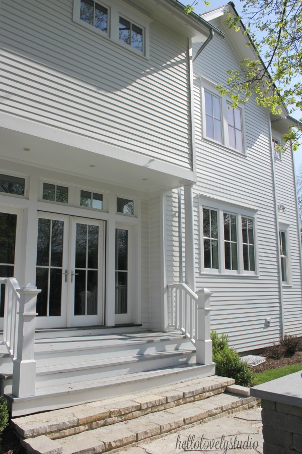 White modern farmhouse exterior with cedar siding, board and batten, metal galvalume roof, and black trim accents. Come see more! Photo by Hello Lovely Studio. #modernfarmhouse #exterior #whitefarmhouse #boardandbatten #housedesign #farmhousearchitecture #hellolovelystudio