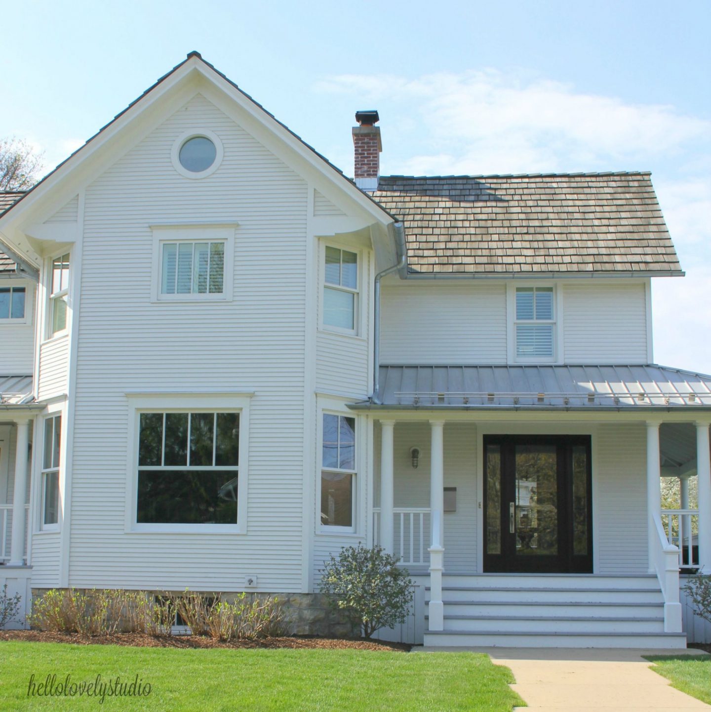 White modern farmhouse exterior with cedar siding, board and batten, metal galvalume roof, and black trim accents. Come see more! Photo by Hello Lovely Studio. #modernfarmhouse #exterior #whitefarmhouse #boardandbatten #housedesign #farmhousearchitecture #hellolovelystudio