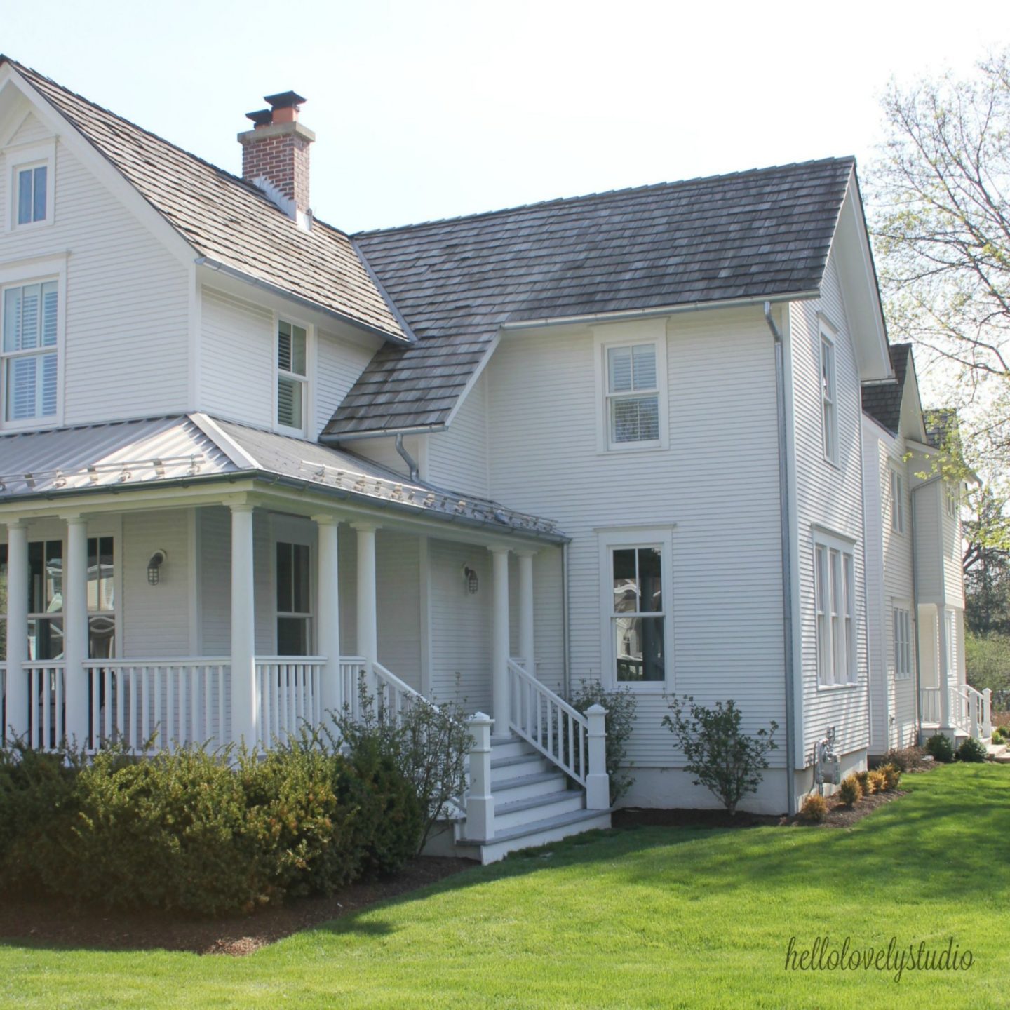 White modern farmhouse exterior with cedar siding, board and batten, metal galvalume roof, and black trim accents. Come see more! Photo by Hello Lovely Studio. #modernfarmhouse #exterior #whitefarmhouse #boardandbatten #housedesign #farmhousearchitecture #hellolovelystudio