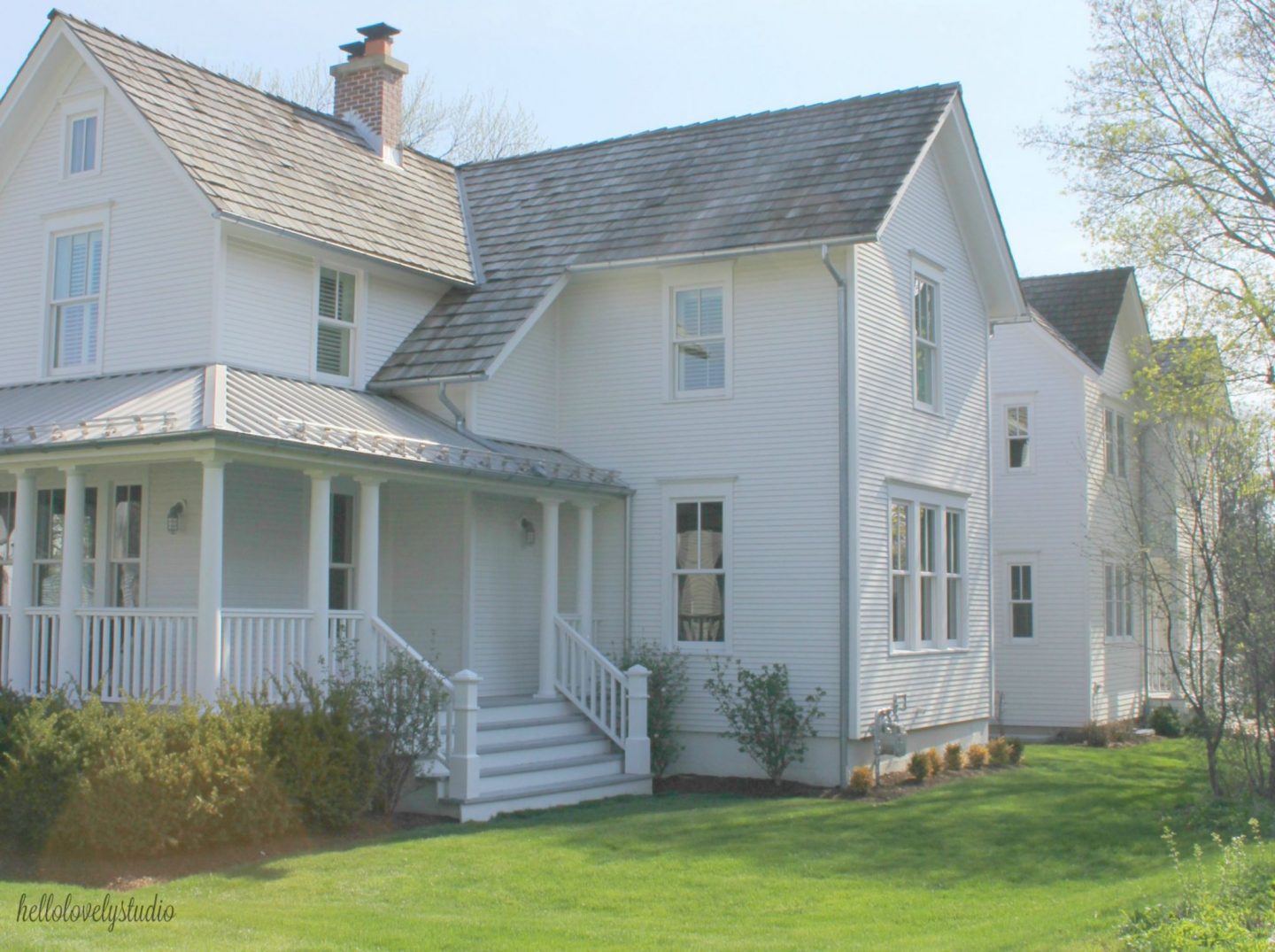 Beautiful white modern farmhouse exterior with cedar siding, board and batten, metal galvalume roof, and black trim accents. Come see more! Photo by Hello Lovely Studio. #modernfarmhouse #exterior #whitefarmhouse #boardandbatten #housedesign #farmhousearchitecture #hellolovelystudio