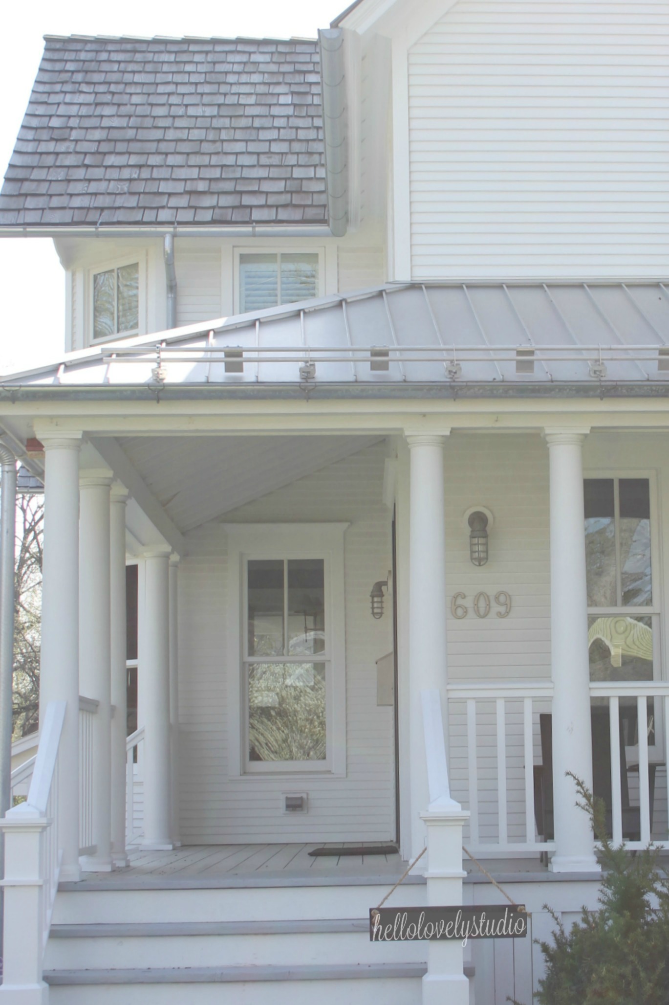 White modern farmhouse exterior with cedar siding, board and batten, metal galvalume roof, and black trim accents. Come see more! Photo by Hello Lovely Studio. #modernfarmhouse #exterior #whitefarmhouse #boardandbatten #housedesign #farmhousearchitecture #hellolovelystudio