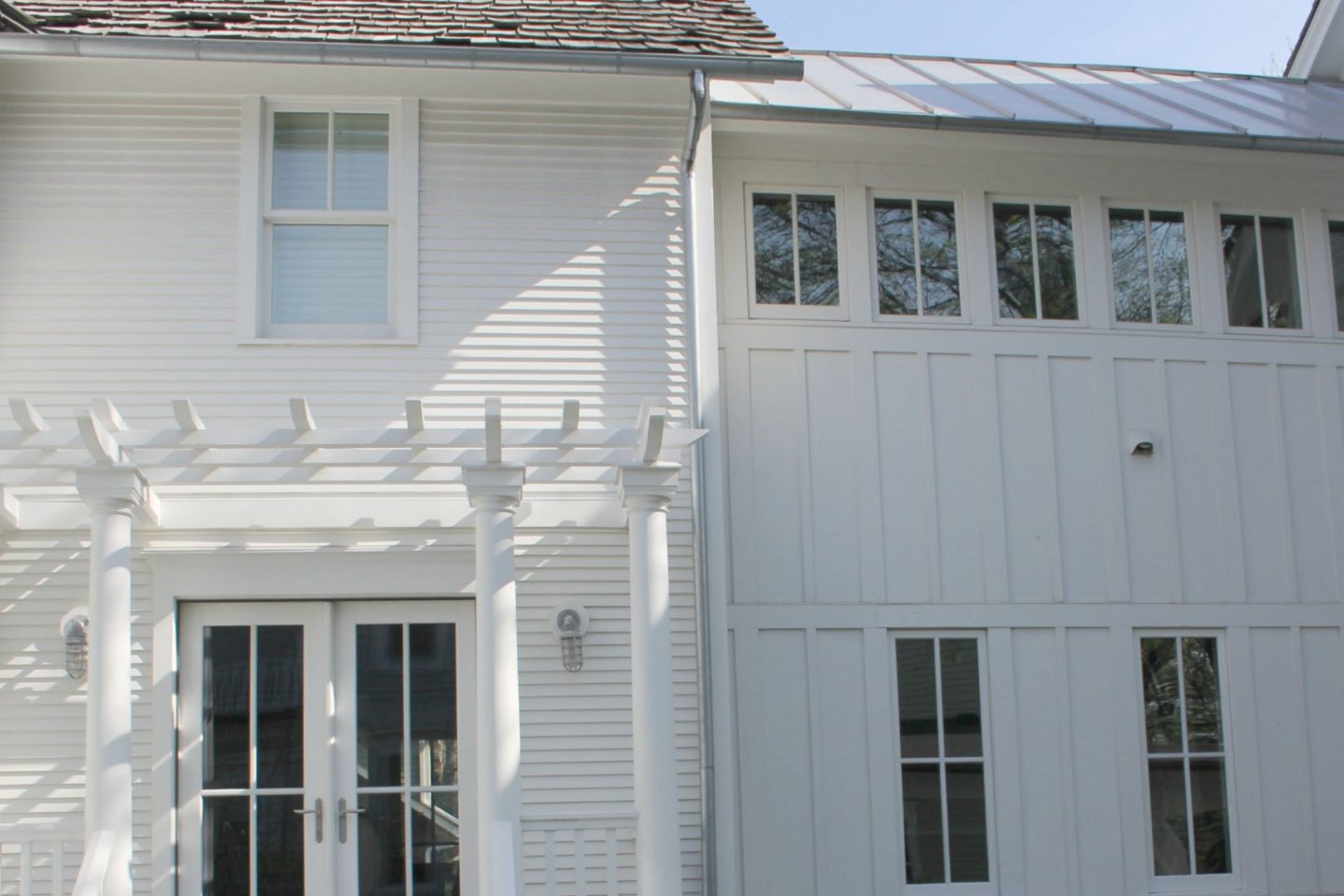 White modern farmhouse exterior with cedar siding, board and batten, metal galvalume roof, and black trim accents. Come see more! Photo by Hello Lovely Studio. #modernfarmhouse #exterior #whitefarmhouse #boardandbatten #housedesign #farmhousearchitecture #hellolovelystudio