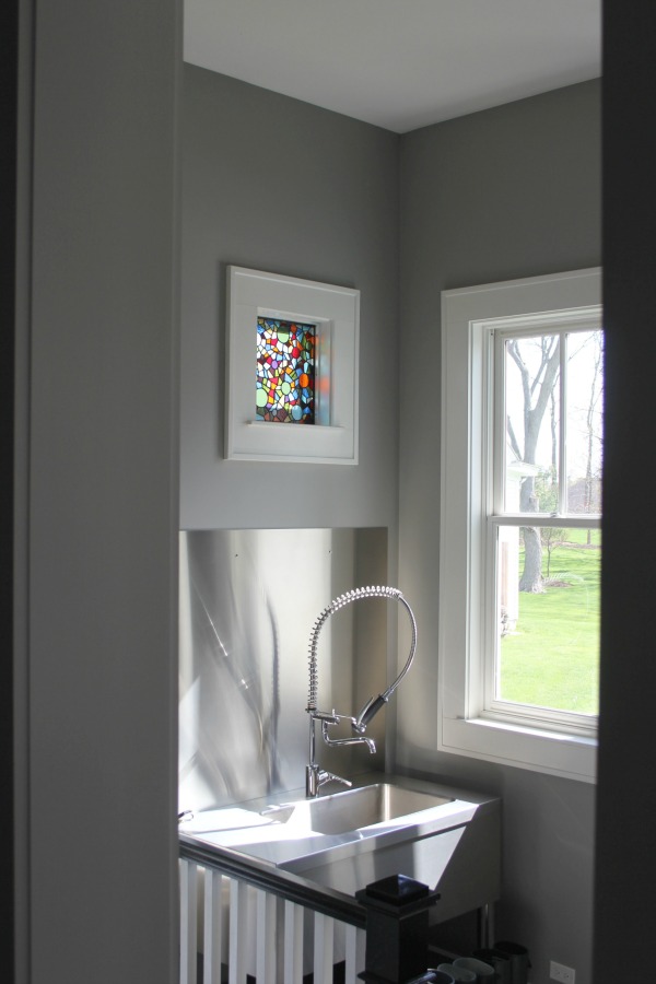 Mud room in a modern farmhouse with Benjamin Moore Stonington Gray walls, stainless steel, and a stained glass window. #benjaminmoorestoningtongray #paintcolors #interiordesign #mudroom