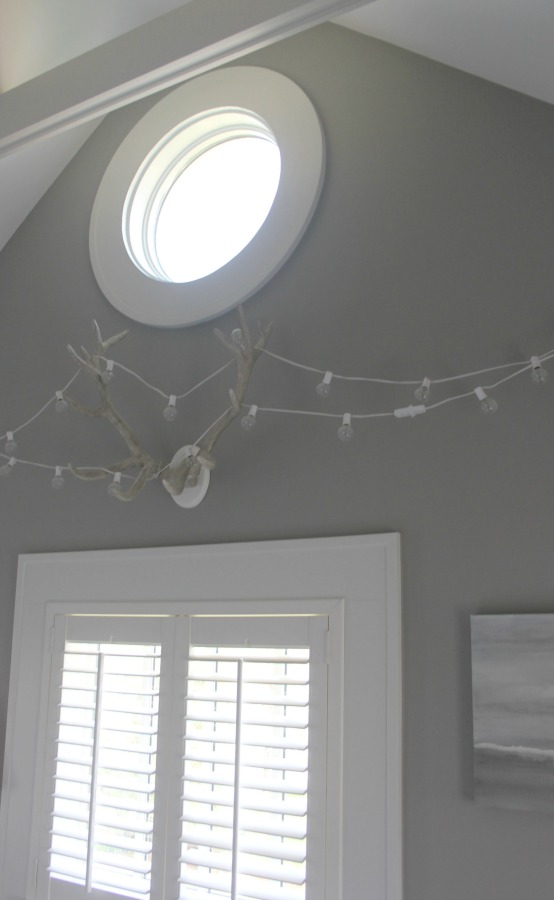 Round window in modern farmhouse bedroom with plantation shutters. Modern Industrial Farmhouse Bedroom Design {2nd Floor Tour}. #modernfarmhouse #bedroom #industrialfarmhouse #greywalls #luxuriousfarmhouse #benjaminmooreplatinum #benjaminmoorestoningtongray