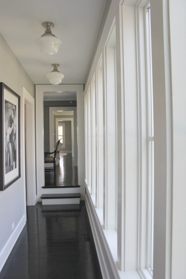 School house lights in a modern farmhouse gallery style hall with medium grey paint colors. #interiordesign #greypaint #paintcolors #blackfloors #industrialfarmhouse 