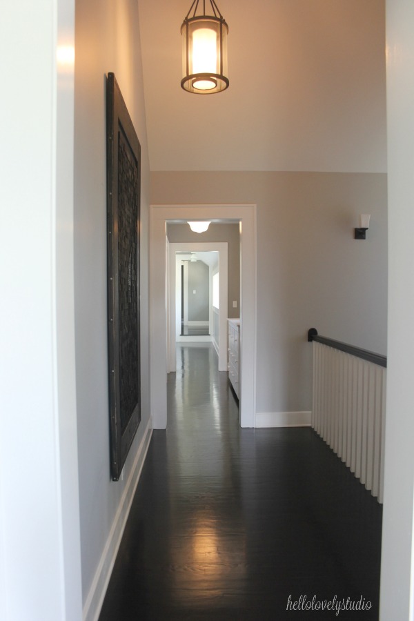 Black flooring, medium grey paint colors, and magnificent architecture in a second floor landing of an industrial farmhouse. #interiordesign #paintcolors #industrialfarmhouse #blackfloors