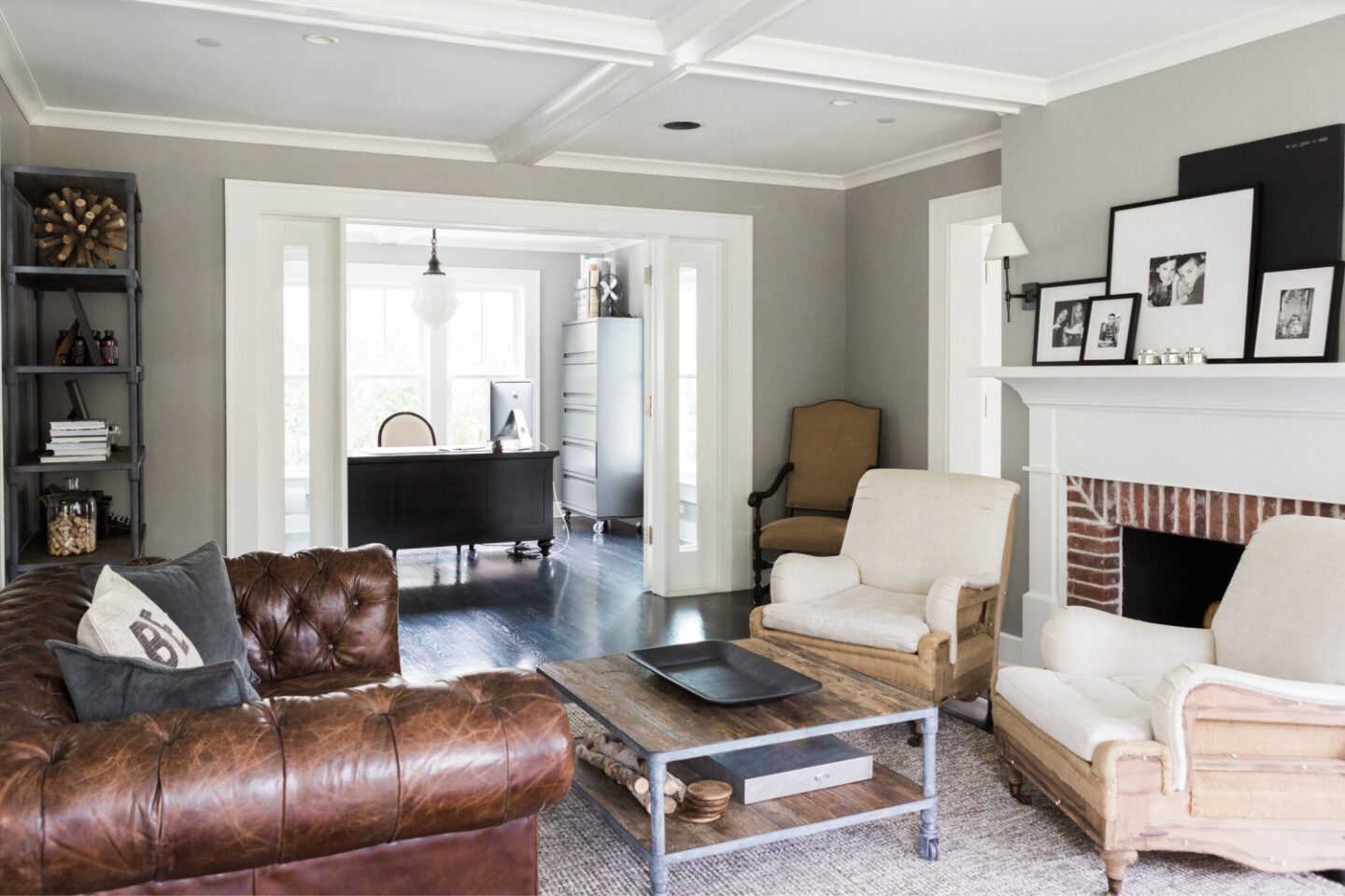 Traditional living room with red brick fireplace, leather Chesterfield sofa, Stonington Gray walls and adjacent home office. #benjaminmoorestoningtongray