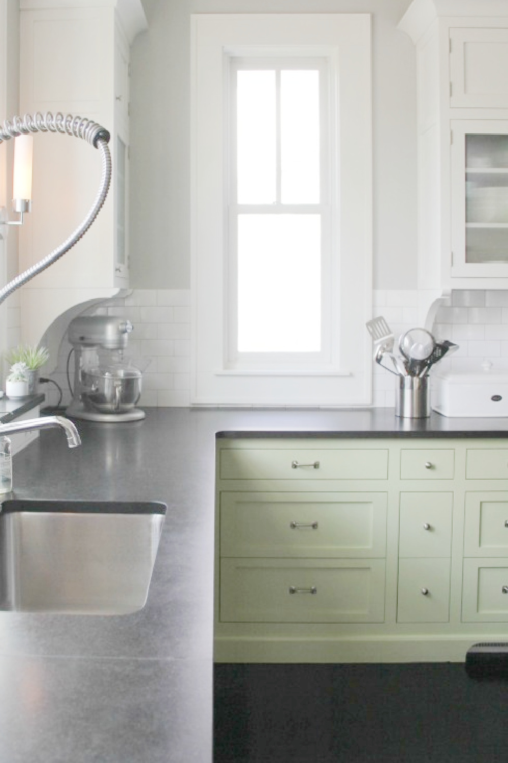 Industrial elements and soapstone countertops in a modern farmhouse kitchen with green cabinets - Hello Lovely Studio.