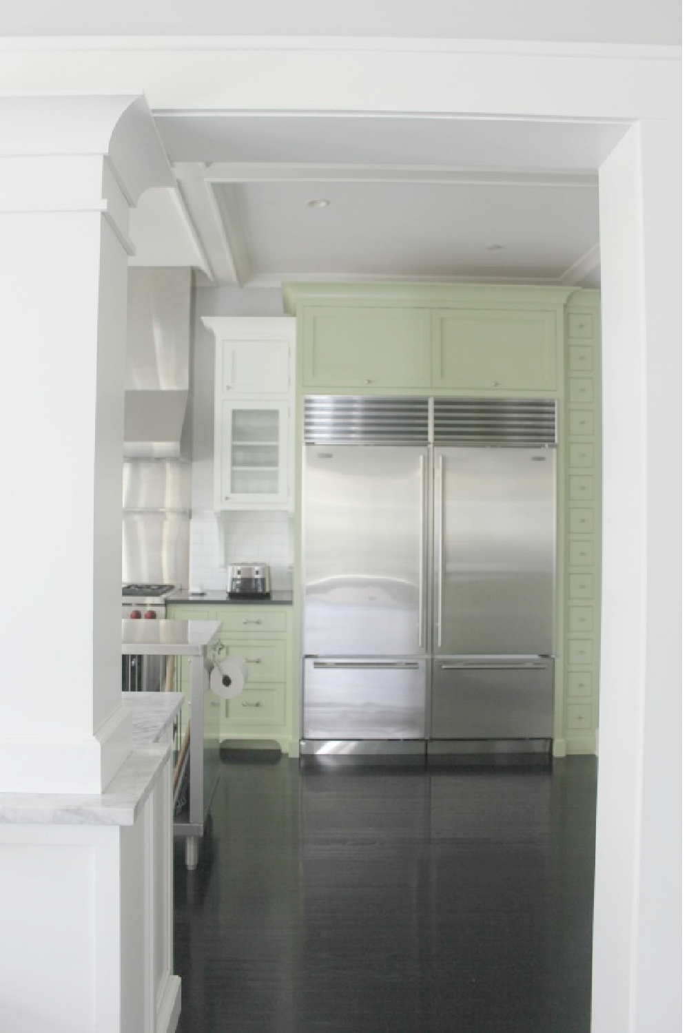 Farmhouse kitchen with two tone cabinets (green and white), soapstone countertops, and black stained hardwood floors - Hello Lovely Studio.