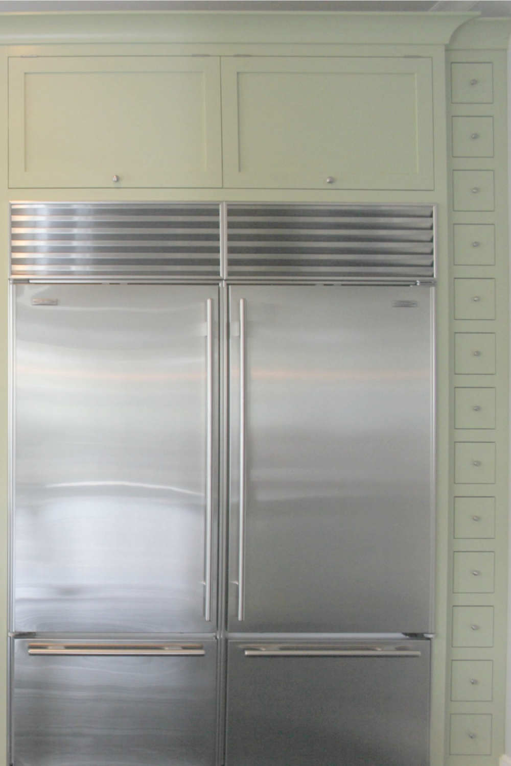 Green cabinets in a classic modern farmhouse kitchen with stainless appliances.