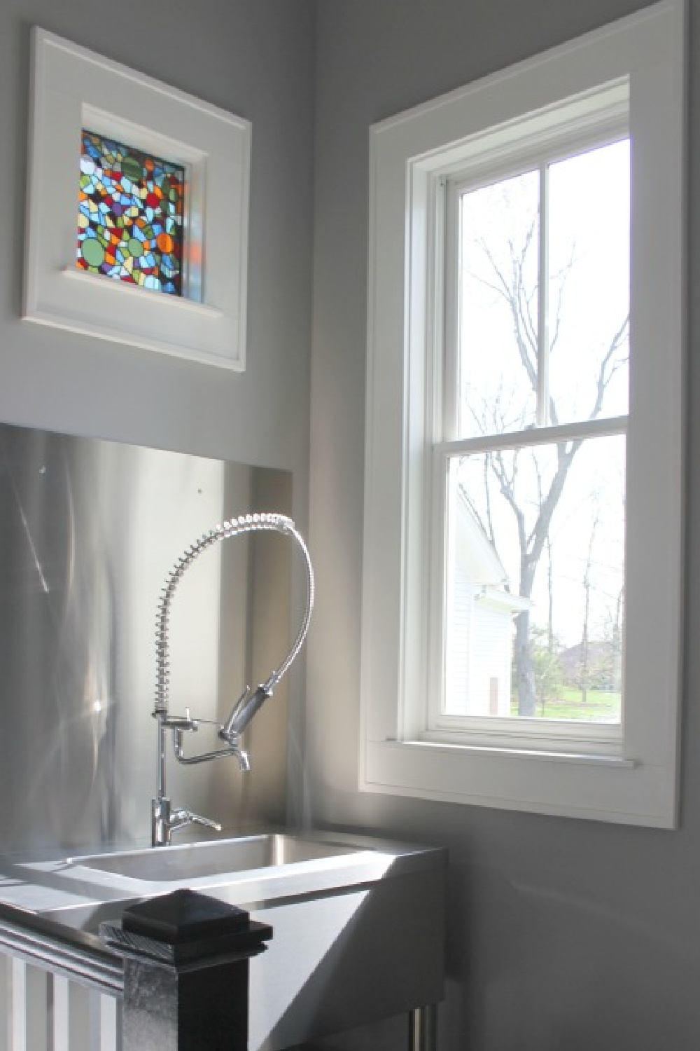 Stainless commercial style sink in mud room with stained glass window - Hello Lovely Studio.