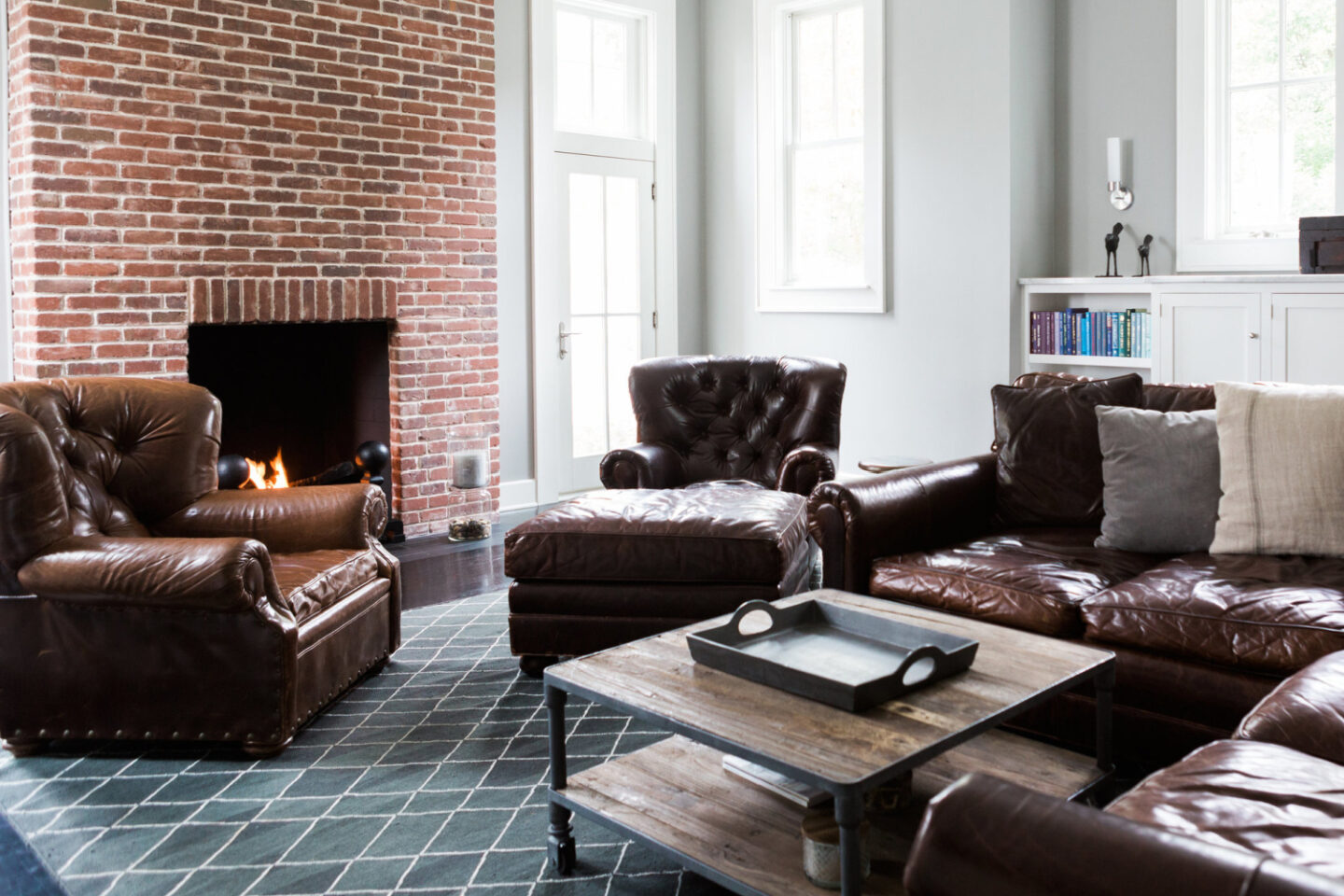 Family room with red brick fireplaceand tufted leather RH furnishings - Hello Lovely Studio.