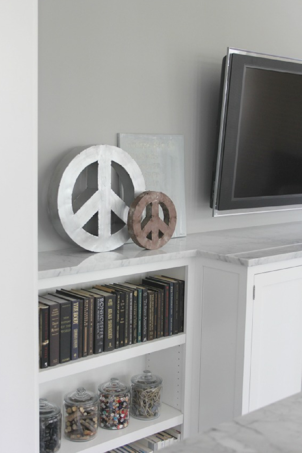 Art work and peace signs on a marble topped shelf in family room - Hello Lovely Studio.