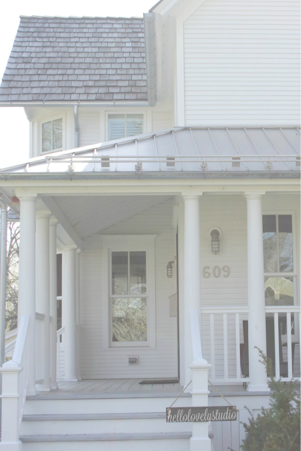 White farmhouse with wrap around porch and metal roof - Hello Lovely Studio.