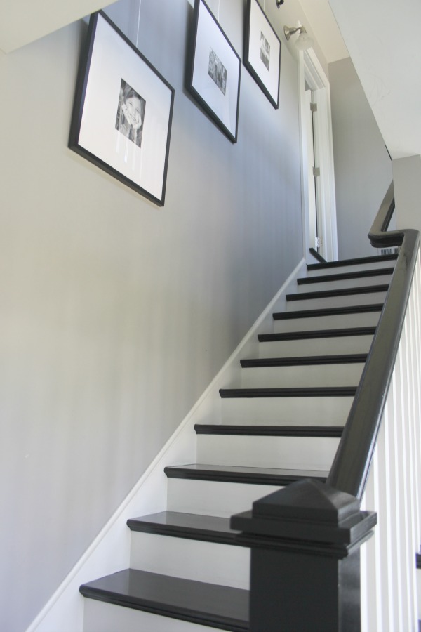 Black painted stairs, grey walls, and white painted stair risers. Farmhouse interior design inspiration for fans of industrial, modern, and traditional farmhouse house designs. This 1875 historical farmhouse in Barrington, Illinois was renovated to a high standard with superior craftsmanship and bespoke design details. Come score ideas for medium grey paint colors on Hello Lovely. #staircase #blackfloors #greypaintcolors