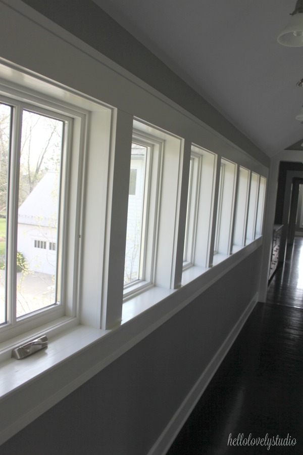 Gallery of windows in upstairs hall. Farmhouse interior design inspiration and medium grey paint color ideas for fans of industrial, modern, and traditional farmhouse house designs. This 1875 historical farmhouse in Barrington, Illinois was renovated to a high standard with superior craftsmanship and bespoke design details.