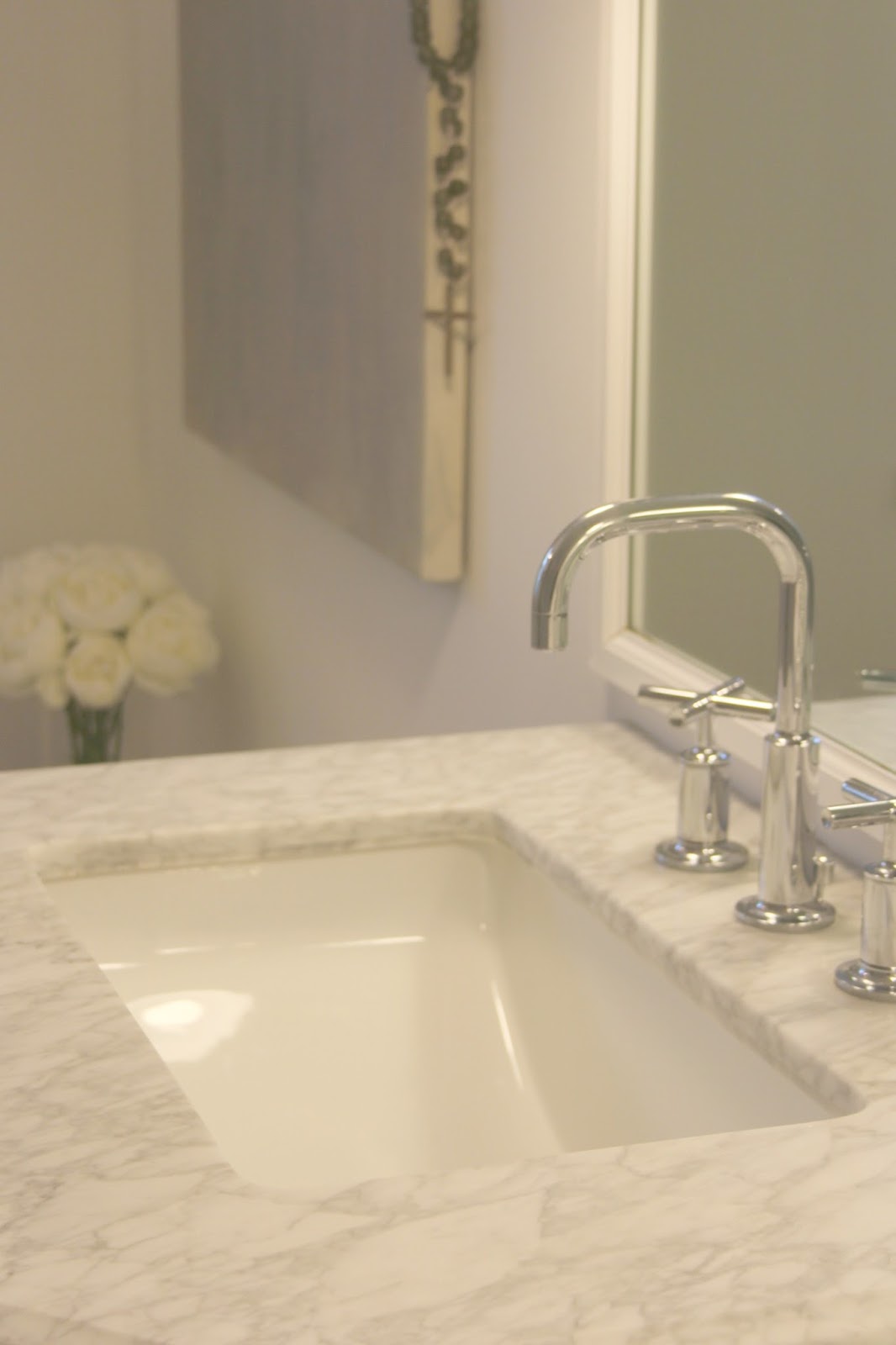 Carrara marble top on vanity in white bathroom. Hello Lovely Studio.