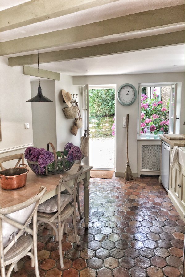 An authentically renovated French farmhouse kitchen near Bordeaux, France, by Vivi et Margot features reclaimed terracotta hex tile floors, rustic ceiling beams, and a custom kitchen by Neptune. Click through for Perfect Light Gray Paint Colors You'll Love as Well as Interior Design Inspiration Photos. #bestgreypaint #paintcolors