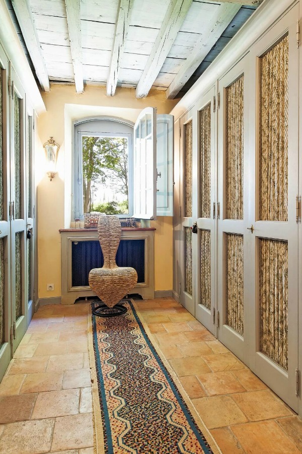 Dressing room with traditional, Old World, rustic elegant closets with shirred fabric fronts. Terracotta tile flooring, and inswing arched window to allow in the breeze and view! Haven In.