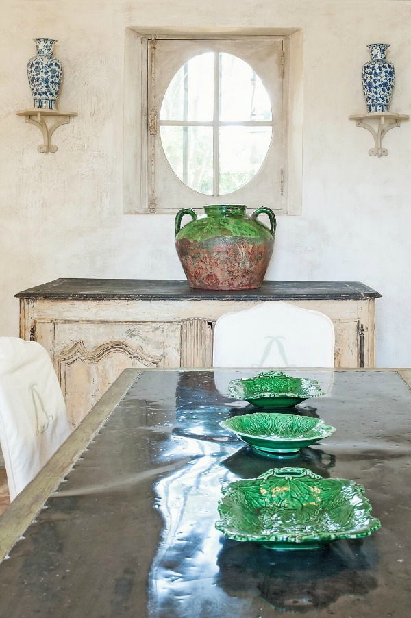 Green accents, plaster walls, and traditional antiques in a dining room in Haven In's stunning French Château Mireille. #diningroom #frenchcountry #traditionalstyle #oldworldstyle