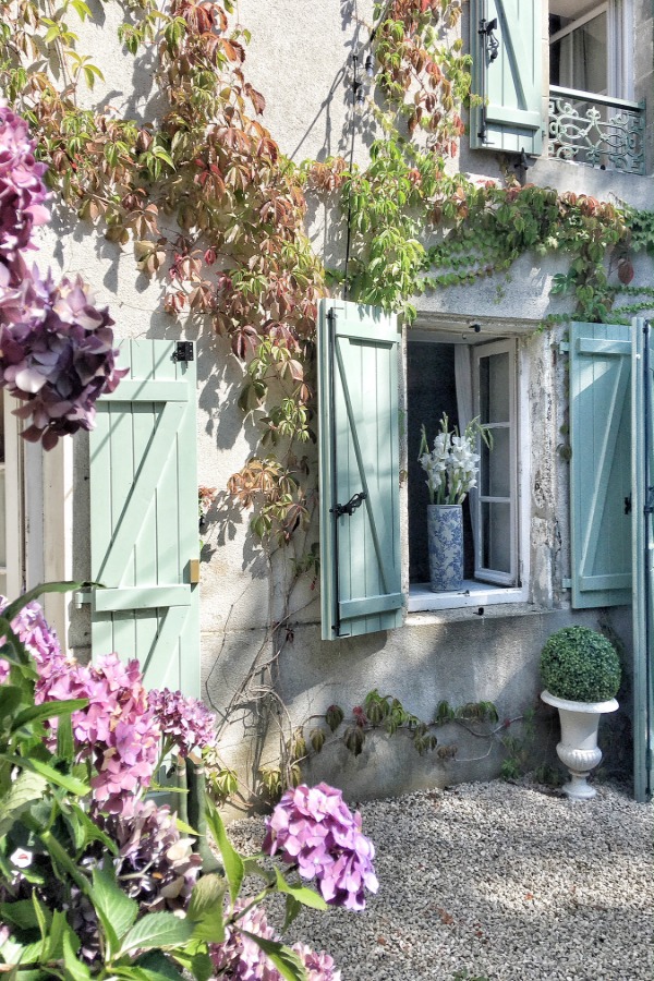 Green shutters on a stone farmhouse exterior with climbing vines. French country rustic design inspiration, house tour, French homewares and market baskets from Vivi et Margot. Enjoy this house tour and ideas to get a rustic European country look! #frenchfarmhouse #frenchhome