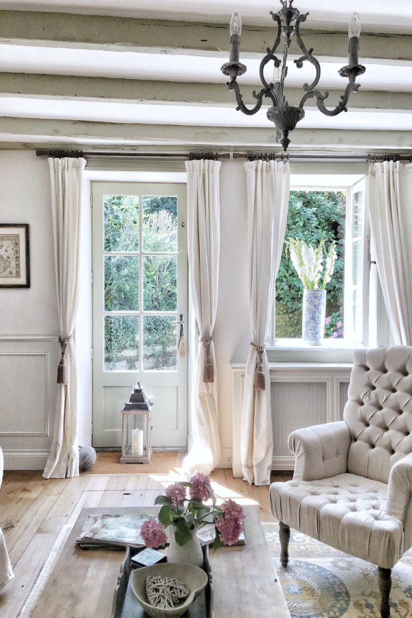 Breezy and unfussy with Belgian linen curtains from Pottery Barn, this French farmhouse living room with white (Farrow and Ball's Strong White) and French Gray accents is as timeless as it is refreshing - Vivi et Margot. Click through for Perfect Light Gray Paint Colors You'll Love as Well as Interior Design Inspiration Photos. #bestgreypaint #paintcolors