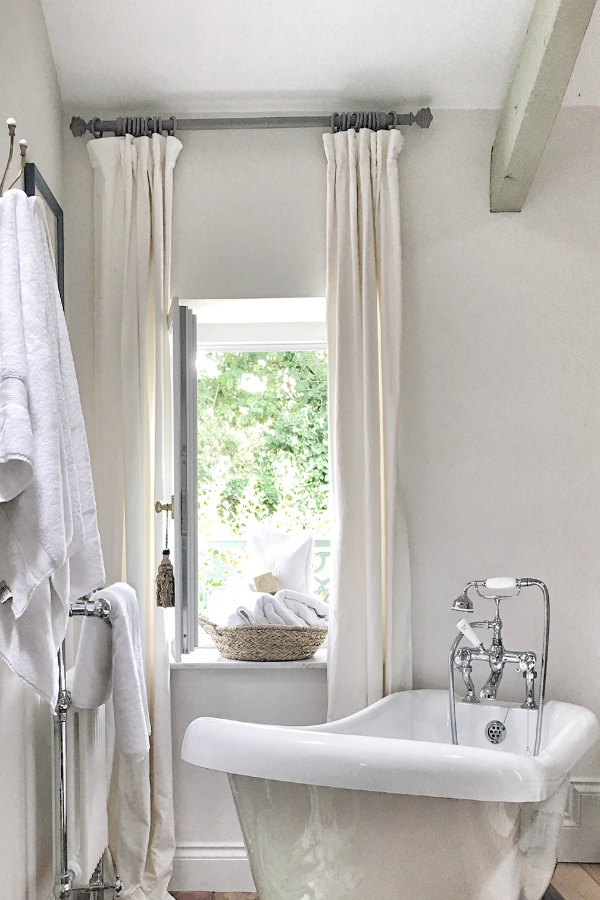 Romantic bathroom in France with clawfoot tub near window. Enjoy this house tour and ideas to get a rustic European country look!