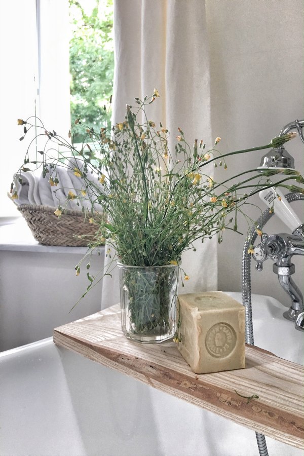 French soap and wildflowers from the French countryside rest on a tray upon a clawfoot tub. #romanticdecor #bathroomdecor #frenchcountry #vivietmargot