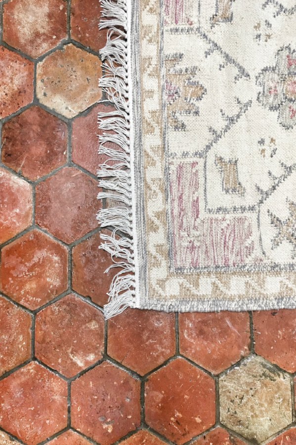 Detail of a lovely pale toned accent rug on terracotta reclaimed antique tiles. #terracottatile #antiquetile #reclaimedtildes #frenchfarmhouse