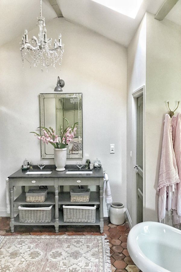 Farrow & Ball Strong White paint color on walls of a romantic bathroom in France with crystal chandelier. Enjoy this house tour and ideas to get a rustic European country look! #frenchcountry #bathroomdesign #farrowandballstrongwhite