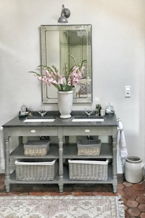 Freestanding vanity with open shelving in a rustic authentic bathroom renovated by Vivi et Margot. #bathroomdesign #bathroomvanity #frenchfarmhouse