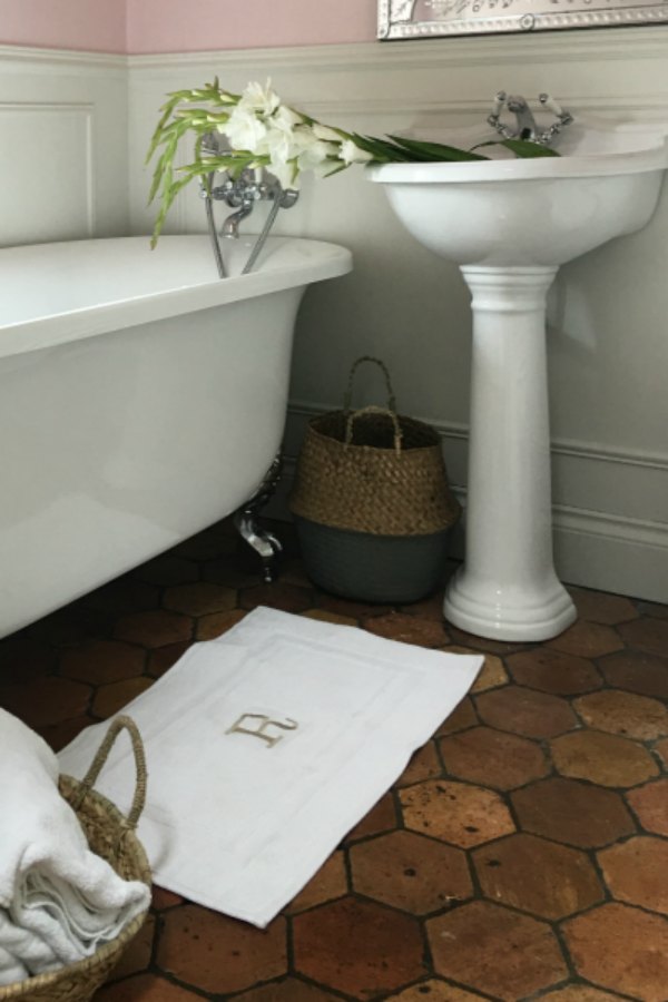 Farrow and Ball Middleton Pink walls in girls bathroom in French farmhouse by Vivi et Margot. Reclaimed antique terracotta tile flooring. Clawfoot tub and pedestal sink. #bathroomdesign #farrowandball #middletonpink #clawfoottub #vivietmargot #terracottatilefloor  #frenchcountry