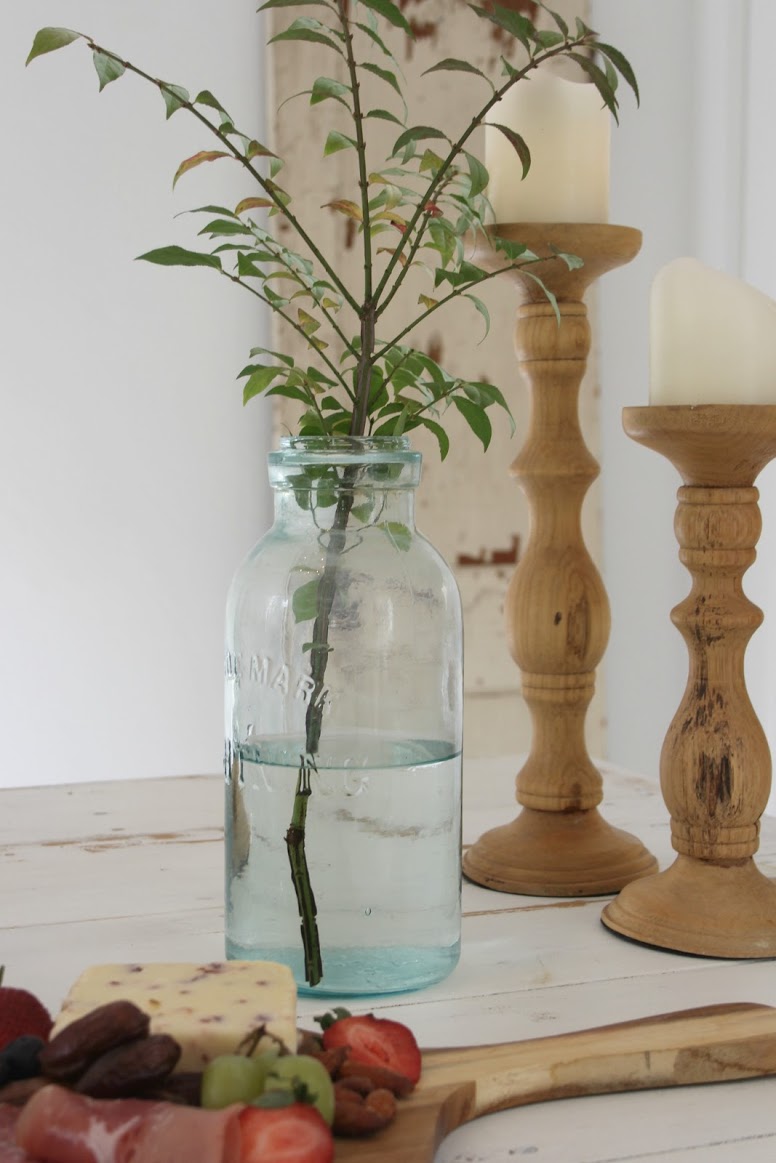 Modern farmhouse romance in a still life with rustic wood candleholders, mason jar with branch, and cheese board. #hellolovelystudio #shabbychic #modernfarmhouse #romanticdecor #frenchfarmhouse