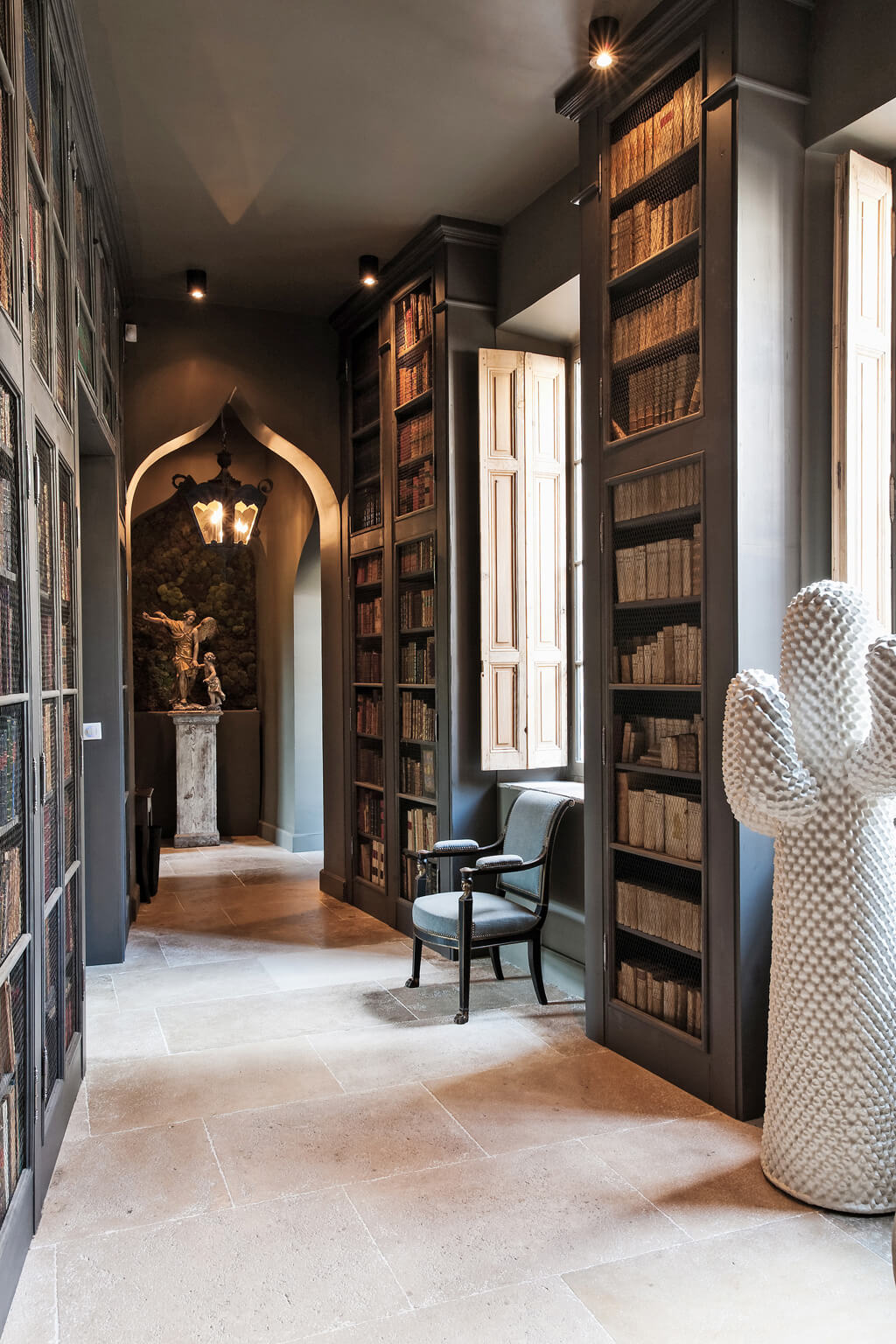 French gray painted built-in bookshelves, limestone, and modern art in an Avignon mansion. Come see a Breathtaking French Château Tour in Provence With Photo Gallery of Historical Architecture, Dramatic Eclectic Interiors & Oddities!